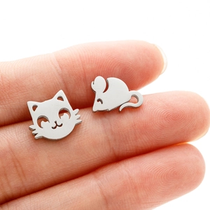 Macro shot of asymmetrical stainless steel cat and mouse stud earrings on fingers