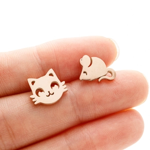 Detail of asymmetric rose gold cat and mouse studs on a finger for size reference