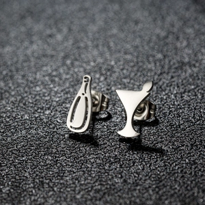 Close-up of asymmetrical silver earrings with unique wine bottle and cocktail glass shapes