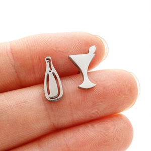 Detailed view of silver asymmetric wine bottle and glass studs held on a finger