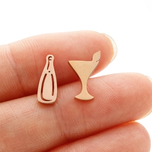 Macro shot of rose gold asymmetrical wine bottle and cocktail glass stud earrings