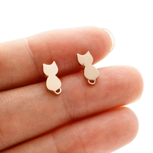 Close-up of cat silhouette earrings in rose gold finish held by hand for size reference