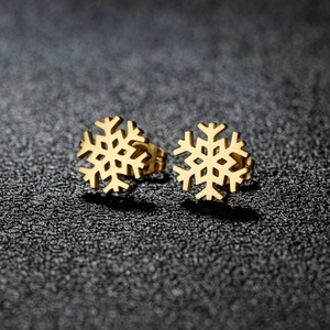 Primer plano de pendientes de copo de nieve dorados con textura de metal cepillado fino