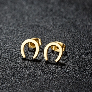 Boucles d'oreilles fer à cheval dorées en forme de U sur un fond noir texturé élégant