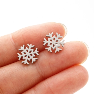 Primer plano de aretes de copo de nieve en los dedos para mostrar el tamaño real mini
