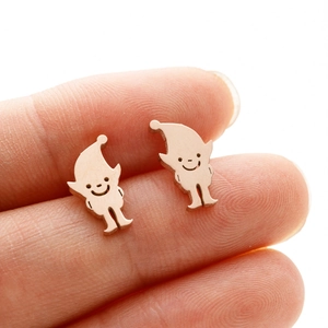 Vue macro de boucles d'oreilles lutin en or rose tenues sur le bout du doigt