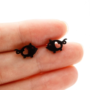 Close-up of cute black pig-shaped stud earrings with heart cut-out detail