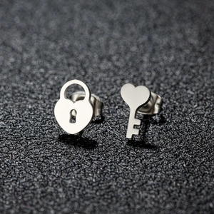 Asymmetric stainless steel heart lock and key stud earrings on elegant black display