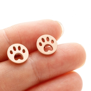 Nahaufnahme der roségoldenen Pfotenabdruck-Ohrstecker an der Fingerspitze für die Größe