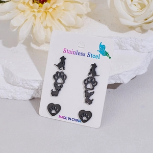 Detailed view of four pairs of black stainless steel dog paw and pet silhouette stud earrings