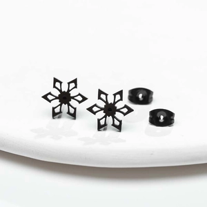 Detail van minimalistische zwarte sneeuwvlok oorbellen met een matte afwerking