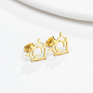 Détail de boucles d'oreilles cœur dorées avec motifs filigranes et bordures perlées