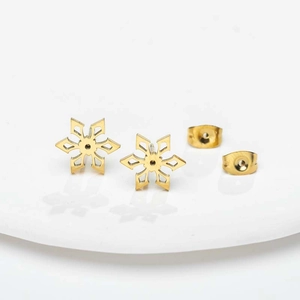 Detail van gouden roestvrijstalen sneeuwvlok oorknopjes op een wit keramisch bord