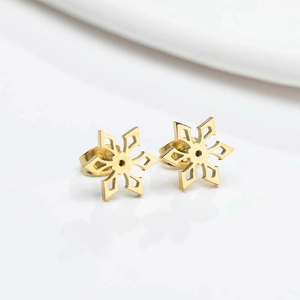 Macro-opname van minimalistische gouden sneeuwvlok oorknopjes met een hol metalen design