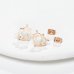 Élégantes boucles d'oreilles cœur évidé en or rose avec motif roue nautique sur socle