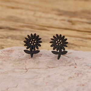 Details von mattschwarzen Sonnenblumen-Ohrsteckern mit Blattdesign auf Naturstein
