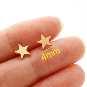Minimalist 4mm gold-tone stainless steel star stud earrings shown on finger
