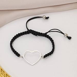 Detail of minimalist black woven bracelet with silver heart charm and adjustable knot