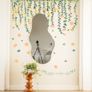 Detail of green vine wall stickers with small yellow flowers next to an irregular mirror