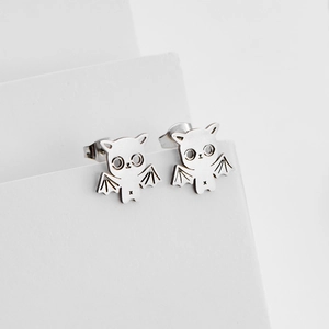 Minimalist silver bat cat stud earrings for Halloween theme on white geometric stand