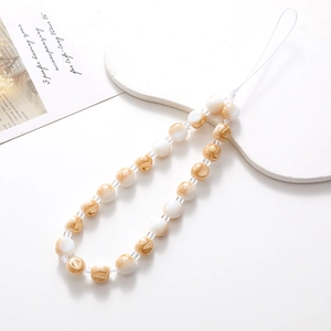 Detail of beaded phone strap with cream and amber marble beads on a white decorative board