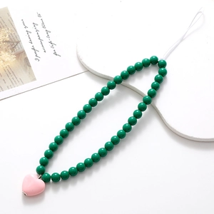 Green beaded phone charm with pink heart pendant on elegant white display stand