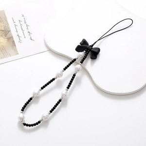 Beaded phone strap with black bow and white irregular pearls on a minimalist lanyard
