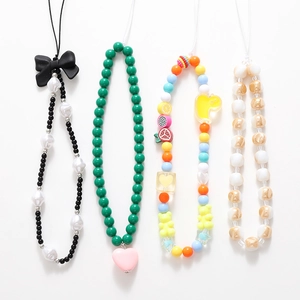 Beaded bow phone charms with heart pendants and colorful resin animals on white background
