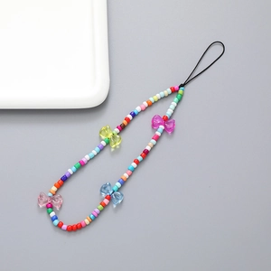 Colorful beaded phone strap with translucent candy bear and bow charms on grey background