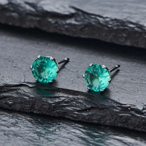 Vue macro de boucles d'oreilles en zircone vert émeraude avec serti à quatre griffes
