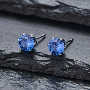 Gros plan sur des boucles d'oreilles clous ronds en zircon bleu sur fond de pierre