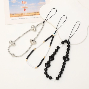 Detailed set of three beaded phone wrist straps with heart and star charms on a white surface