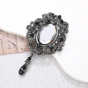 Vintage gunmetal brooch with oval crystal and water drop pendant on white background