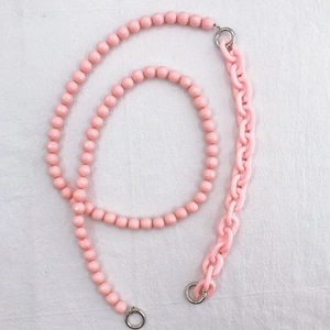 Detail of pink acrylic bead and plastic chain strap with silver metal rings for bags