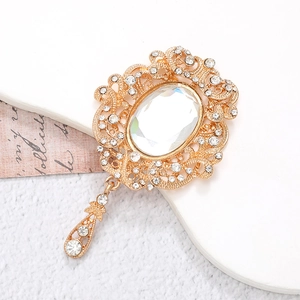 Macro shot of vintage gold brooch with clear oval gemstone and teardrop pendant detail