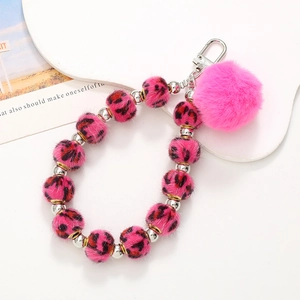 Detail of pink faux fur pom pom and leopard print plush bead phone strap with metal clasp