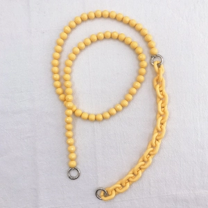 Macro detail of bright yellow resin bead chain with silver metal spring clasps