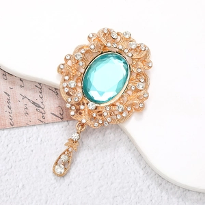 Vintage gold alloy brooch with emerald green gemstone and dangling teardrop pendant