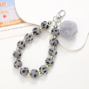 Detail of leopard print plush beads phone strap with fluffy pom pom and silver metal clasp