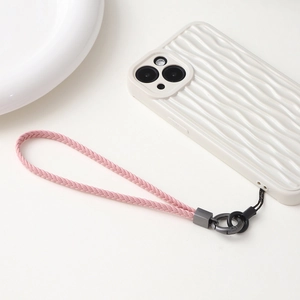 Gros plan sur la dragonne en cuir tressé rose avec fermoir en métal gris sur le téléphone