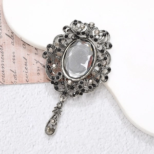 Detail of vintage silver brooch with dark grey rhinestones and elegant teardrop pendant