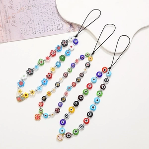 Bijou de téléphone artisanal avec perles fleurs et œil porte-bonheur sur fond blanc épuré