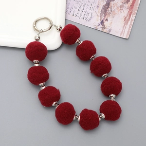 Détail de pompons en peluche rouge vin avec perles argentées et fermoir anneau métal