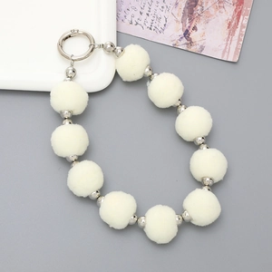 Détail du bracelet en pompons blancs et perles argentées avec fermoir à ressort en métal