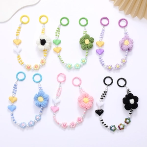 Detail view of colorful beaded phone straps featuring plush woven flowers and pearls