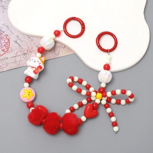 Détail du porte-clés perlé avec chat porte-bonheur, pompon et pendentif coeur sur fond blanc