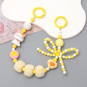Détail de la breloque Maneki Neko avec perles, cœur jaune et pompons doux
