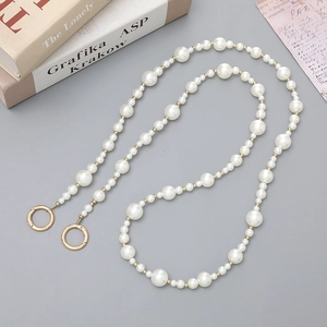 Dettaglio della tracolla in perle sfumate con inserti dorati e fibbie metalliche