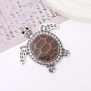 Macro shot of silver alloy turtle pendant with brown enamel shell and sparkling rhinestones