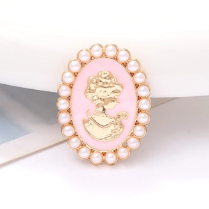 Detalle de broche estilo camafeo con silueta dorada y borde de perlas blancas